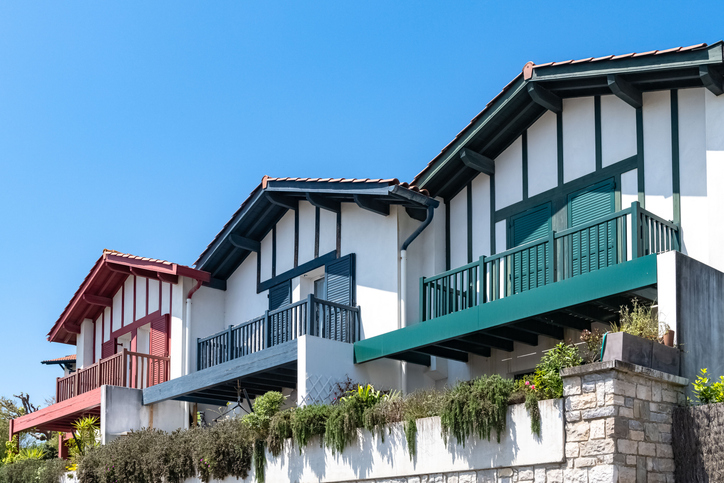 Maisons basques aux colombages verts, bleus et rouges sous un ciel bleu à Biarritz
