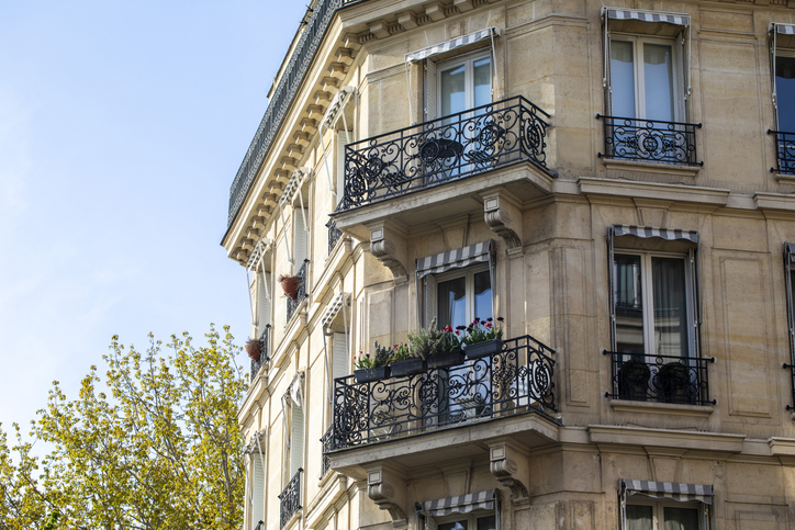 Façade haussmannienne avec balcons en fer forgé et stores rayés, Paris